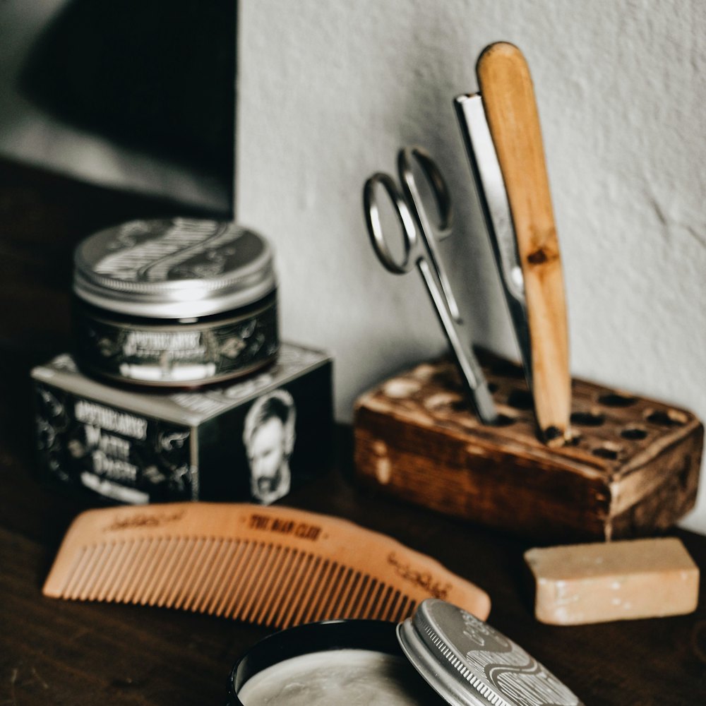 Pomade, comb, razor and scissors on a wooden counter