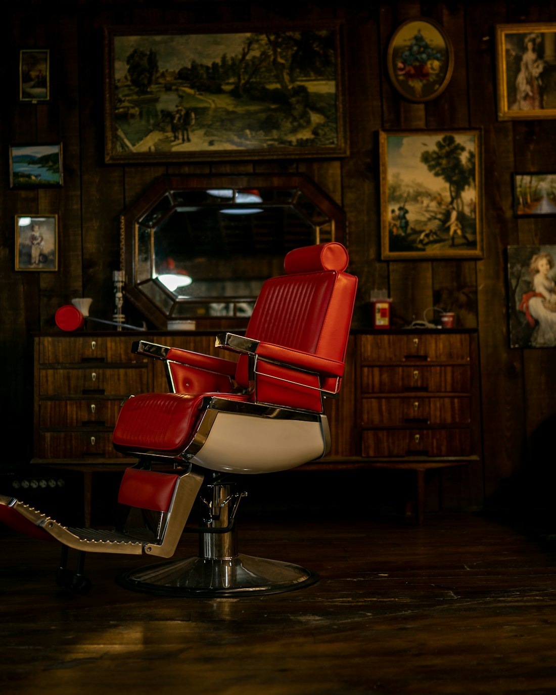 Red leather barber chair surrounded by vintage frames