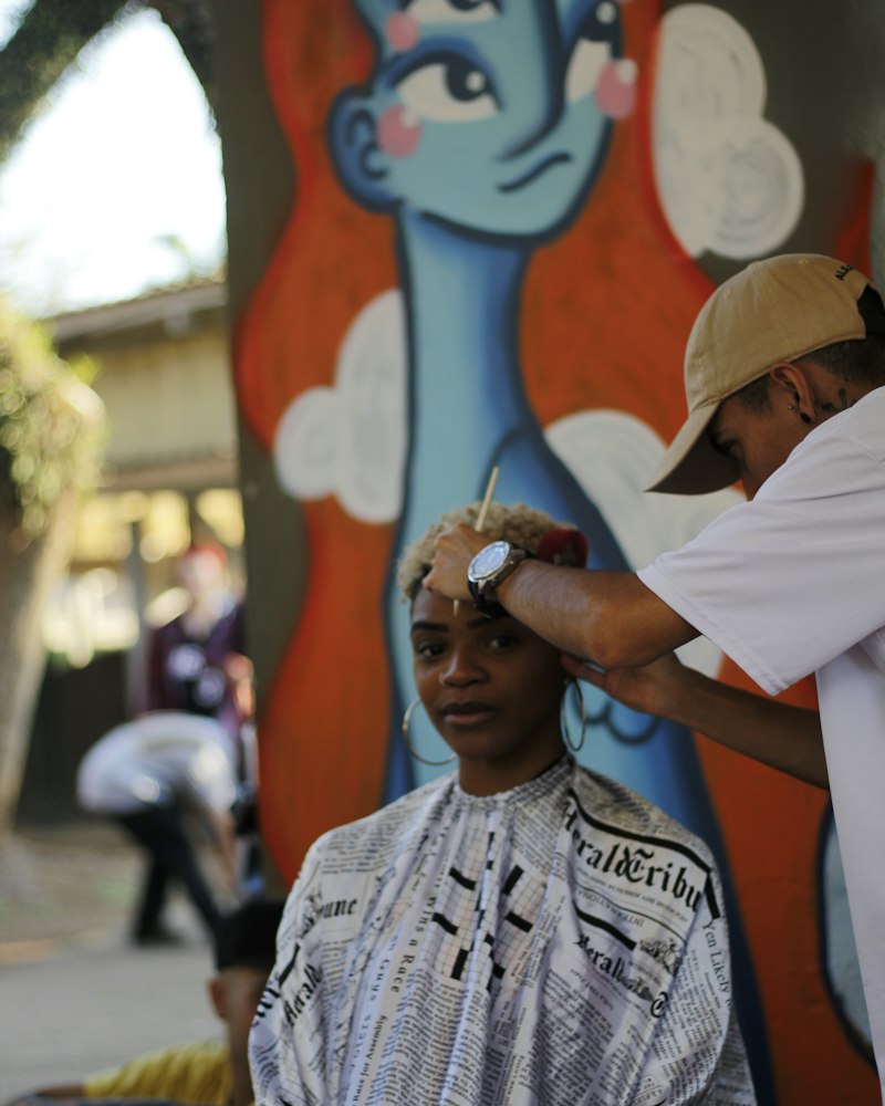 Barber cutting a young client’s hair beside a painted mural